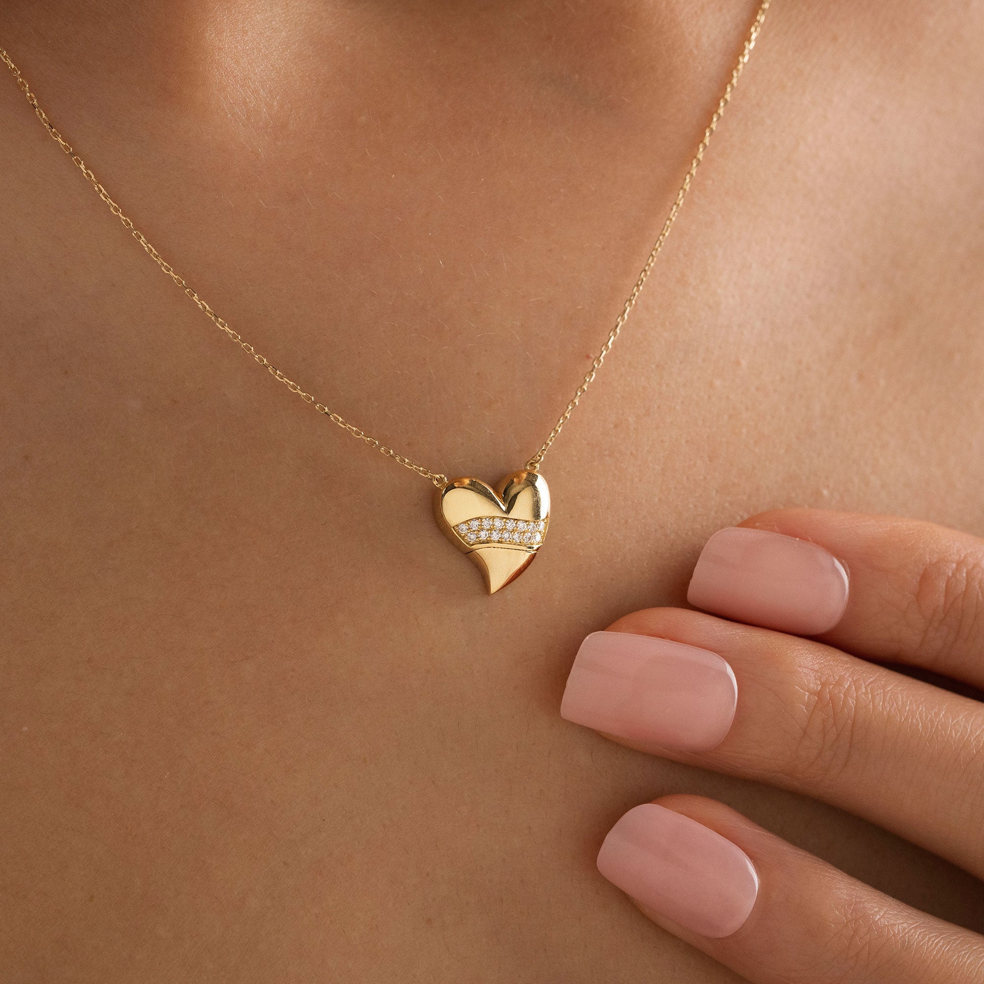Arel Custom Jewelry 14k solid gold stationary necklace featuring a 3D domed heart pendant with a horizontal pave diamond band on a model.