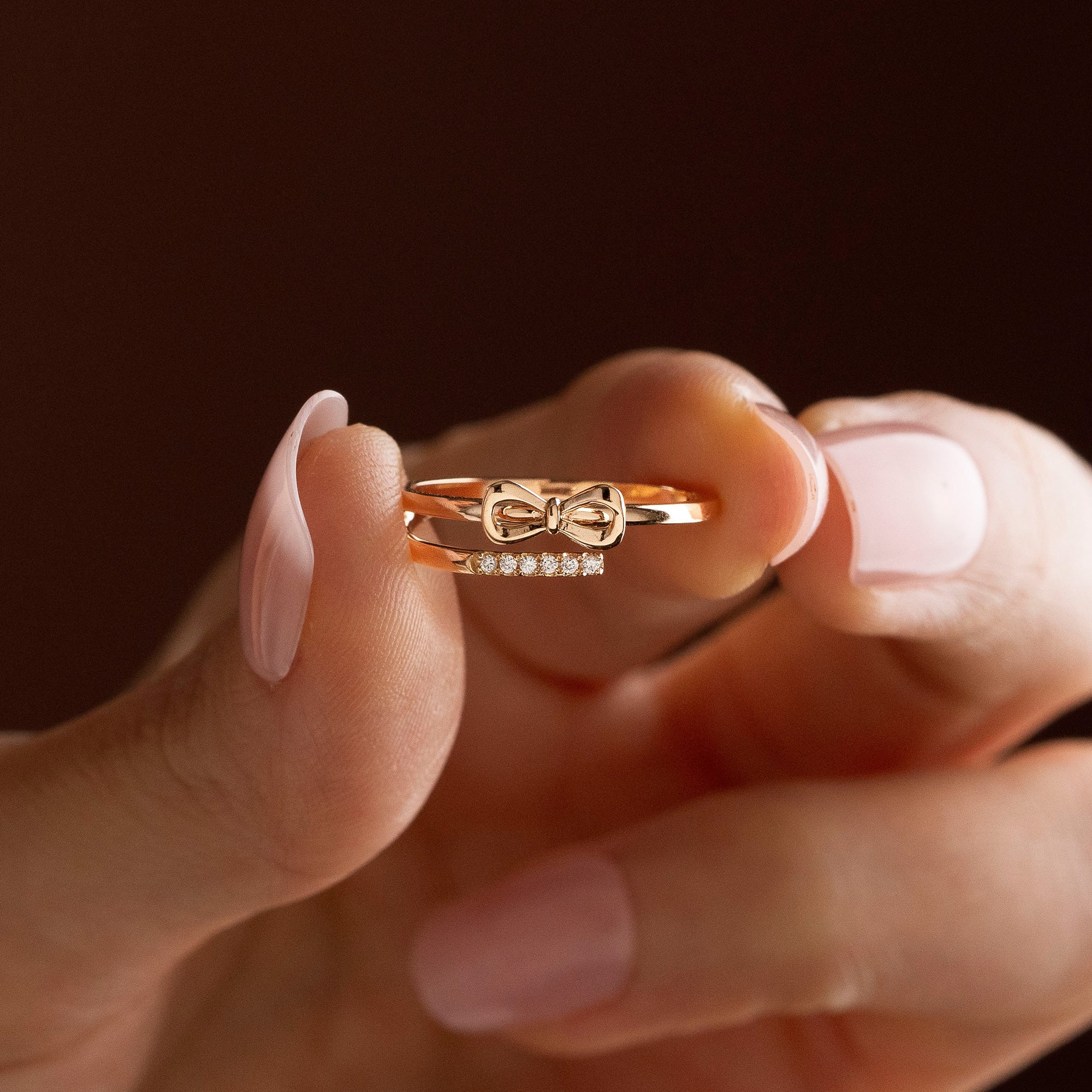 Arel Custom Jewelry 14k solid gold double band wrap ring featuring a polished bow and a pave diamond row on a model's finger.