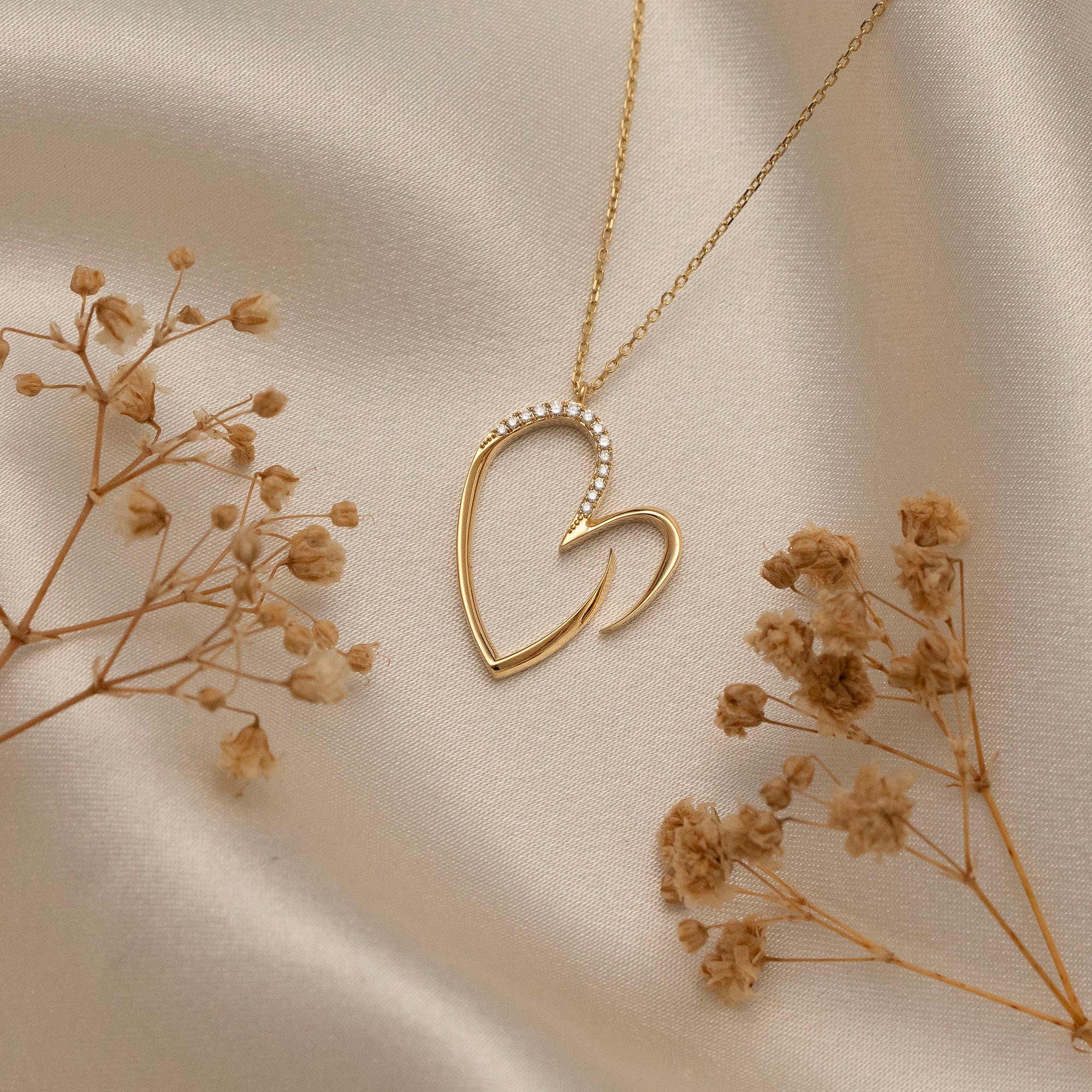 Arel Custom Jewelry 14k solid gold asymmetrical open heart necklace featuring half pave diamonds on a model.