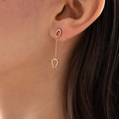 Arel Custom Jewelry 14k solid gold drop earring featuring an oval loop stud and dangling diamond horseshoe charm on a model.