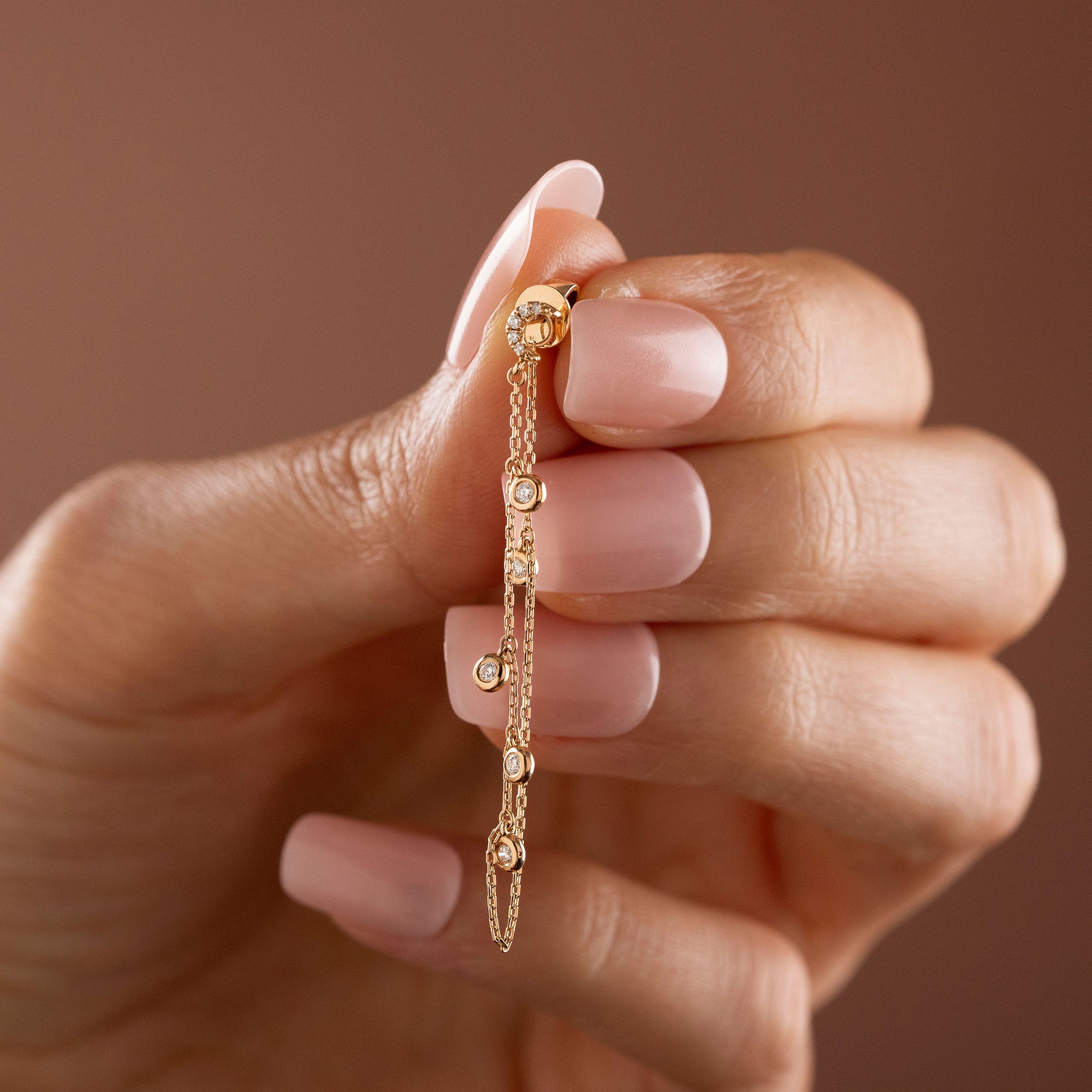14k solid gold drape chain earring featuring a pave diamond crescent moon stud and bezel diamonds on a model