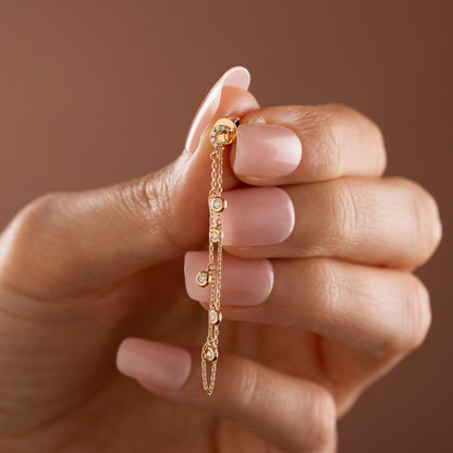 14k solid gold drape chain earring featuring a pave diamond crescent moon stud and bezel diamonds on a model