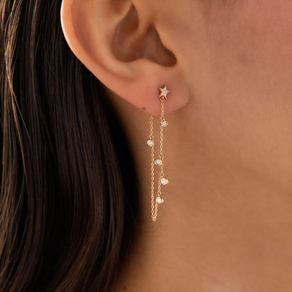 Dainty 14k gold front-to-back chain earring featuring a diamond star stud and bezel-set diamond drops on a model.
