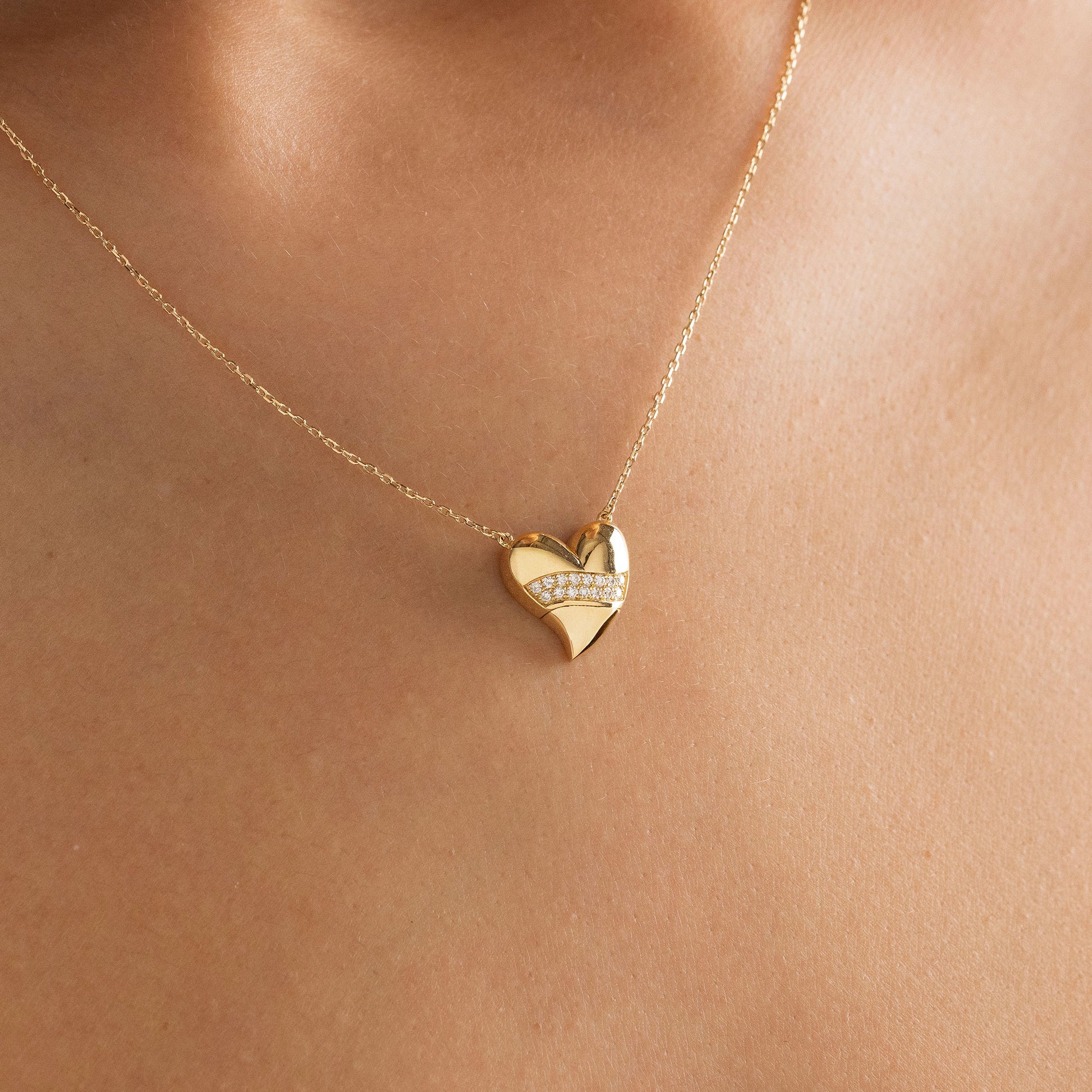 Arel Custom Jewelry 14k solid gold stationary necklace featuring a 3D domed heart pendant with a horizontal pave diamond band on a model.