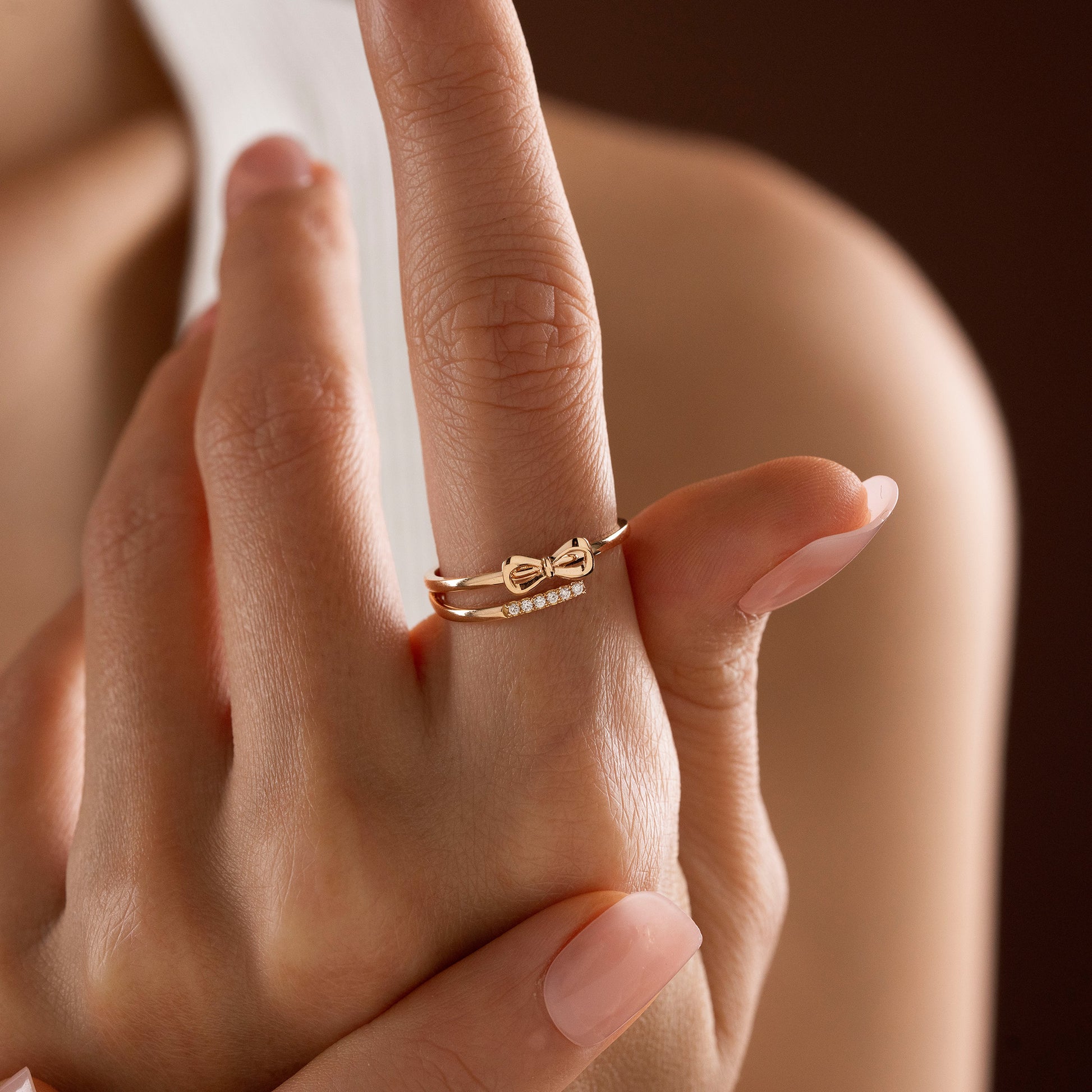 Arel Custom Jewelry 14k solid gold double band wrap ring featuring a polished bow and a pave diamond row on a model's finger.