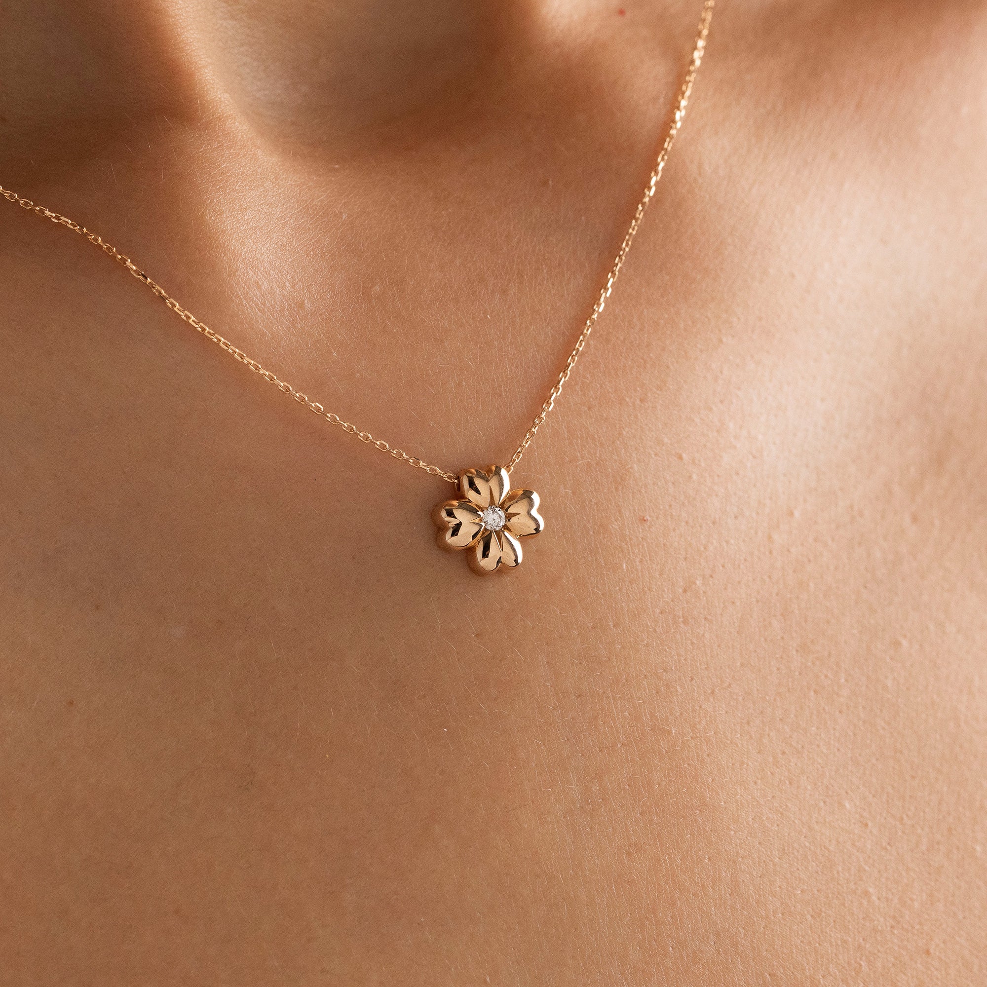 Arel Custom Jewelry 14k solid gold minimalist necklace featuring a four leaf clover pendant with a center diamond on a model.