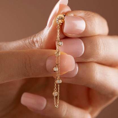 14k solid gold drape chain earring featuring a pave diamond crescent moon stud and bezel diamonds on a model