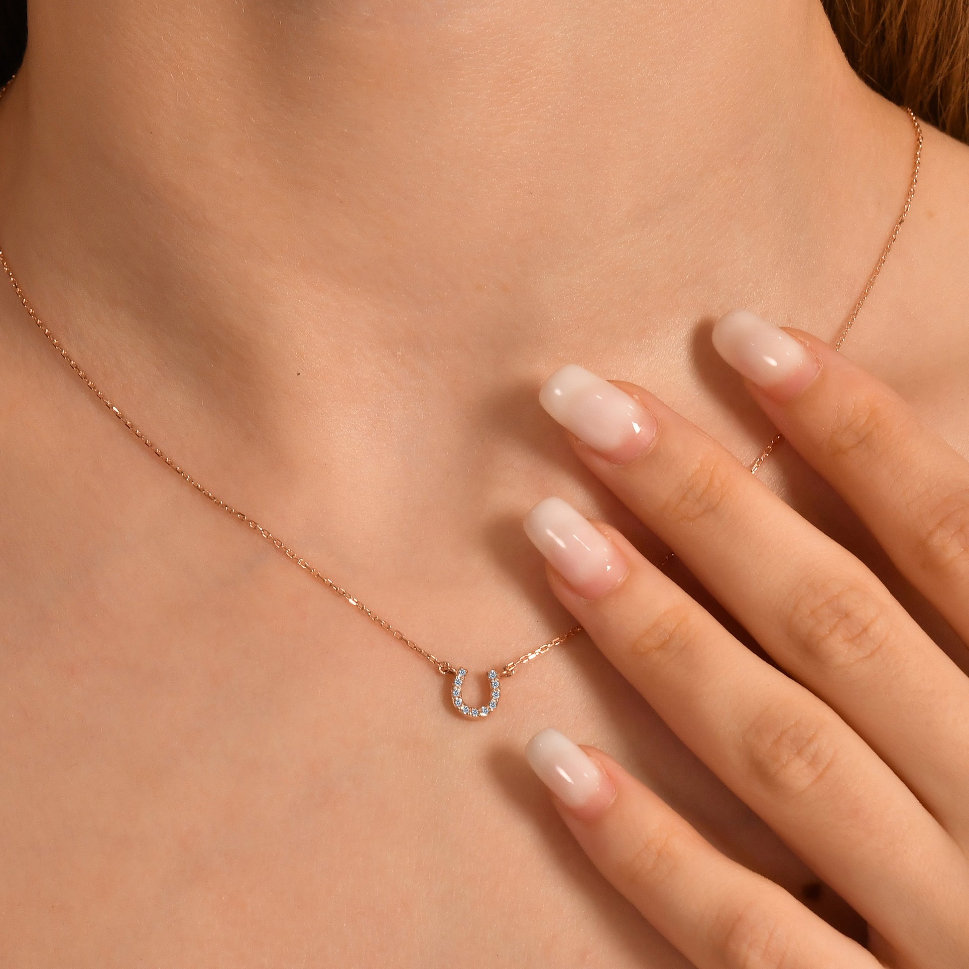 Arel Custom Jewelry 14k solid gold dainty necklace featuring a stationary pave diamond horseshoe pendant on a model.