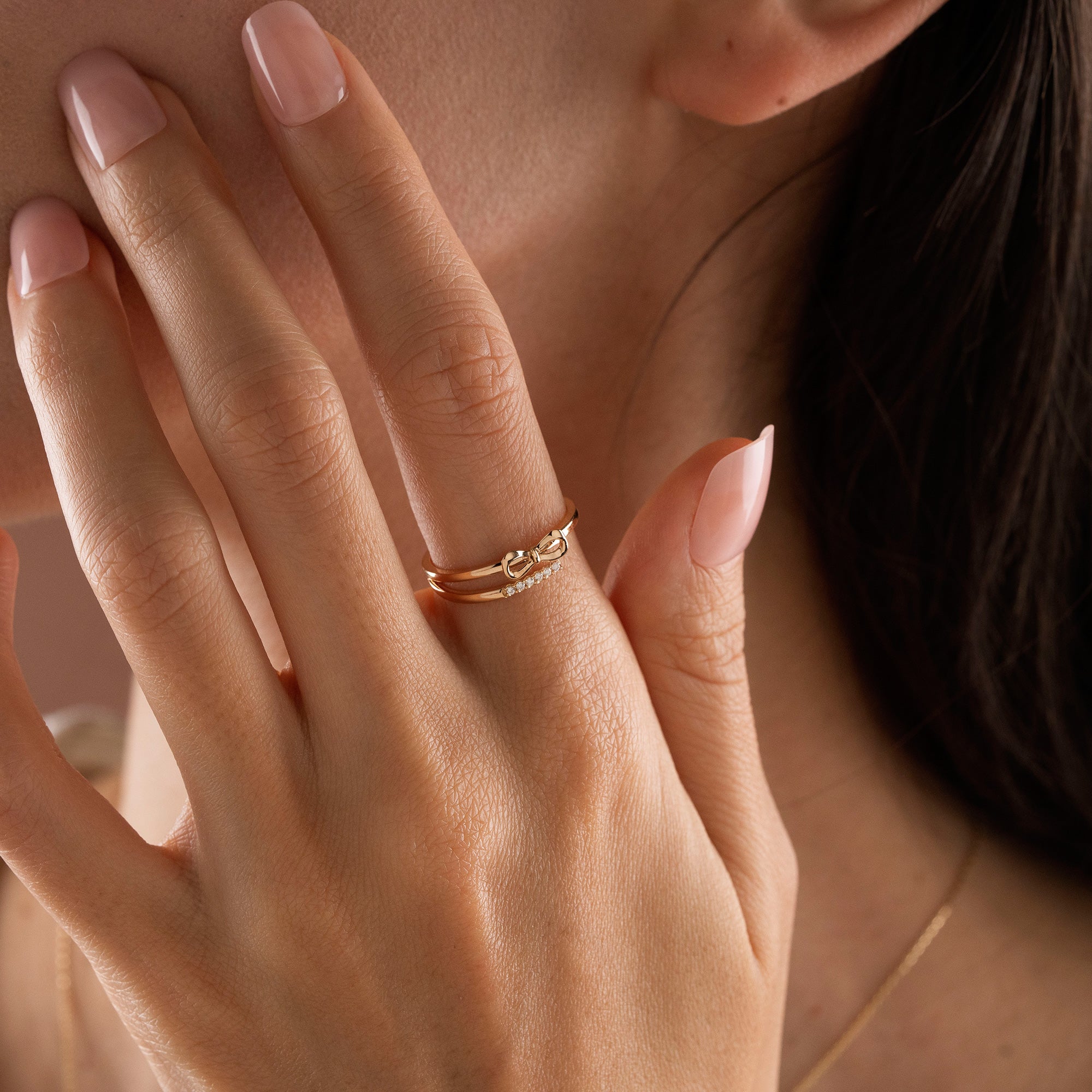 Arel Custom Jewelry 14k solid gold double band wrap ring featuring a polished bow and a pave diamond row on a model's finger.