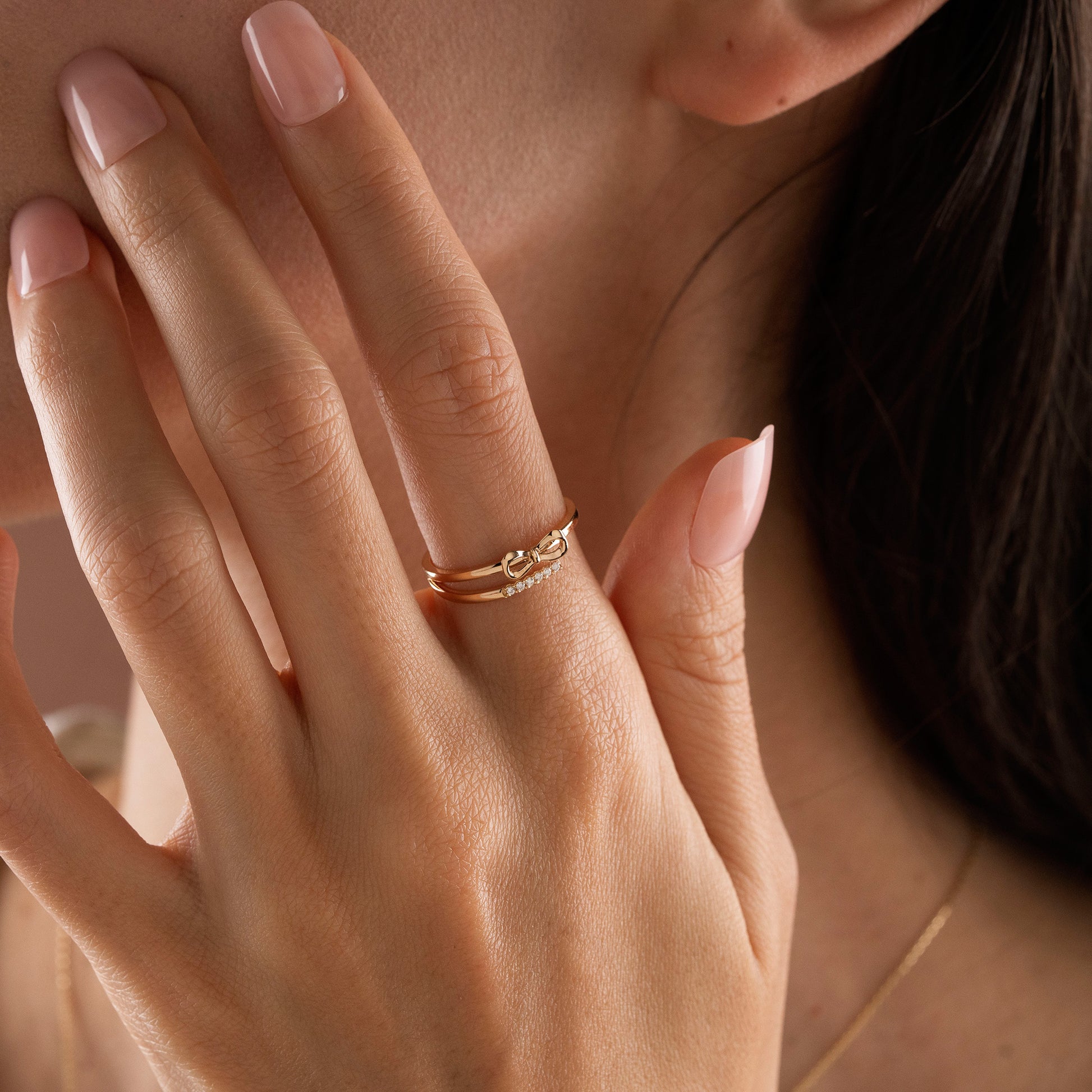 Arel Custom Jewelry 14k solid gold double band wrap ring featuring a polished bow and a pave diamond row on a model's finger.