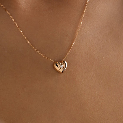 Arel Custom Jewelry 14k solid gold necklace featuring a polished puffed heart pendant with a starburst set center diamond on a model.