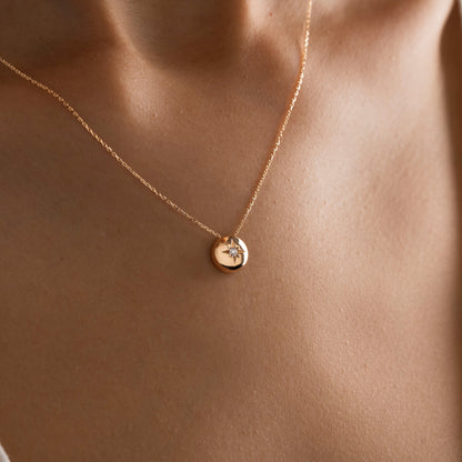 Arel Custom Jewelry 14k solid gold necklace featuring a polished domed pendant with a starburst set center diamond on a model.