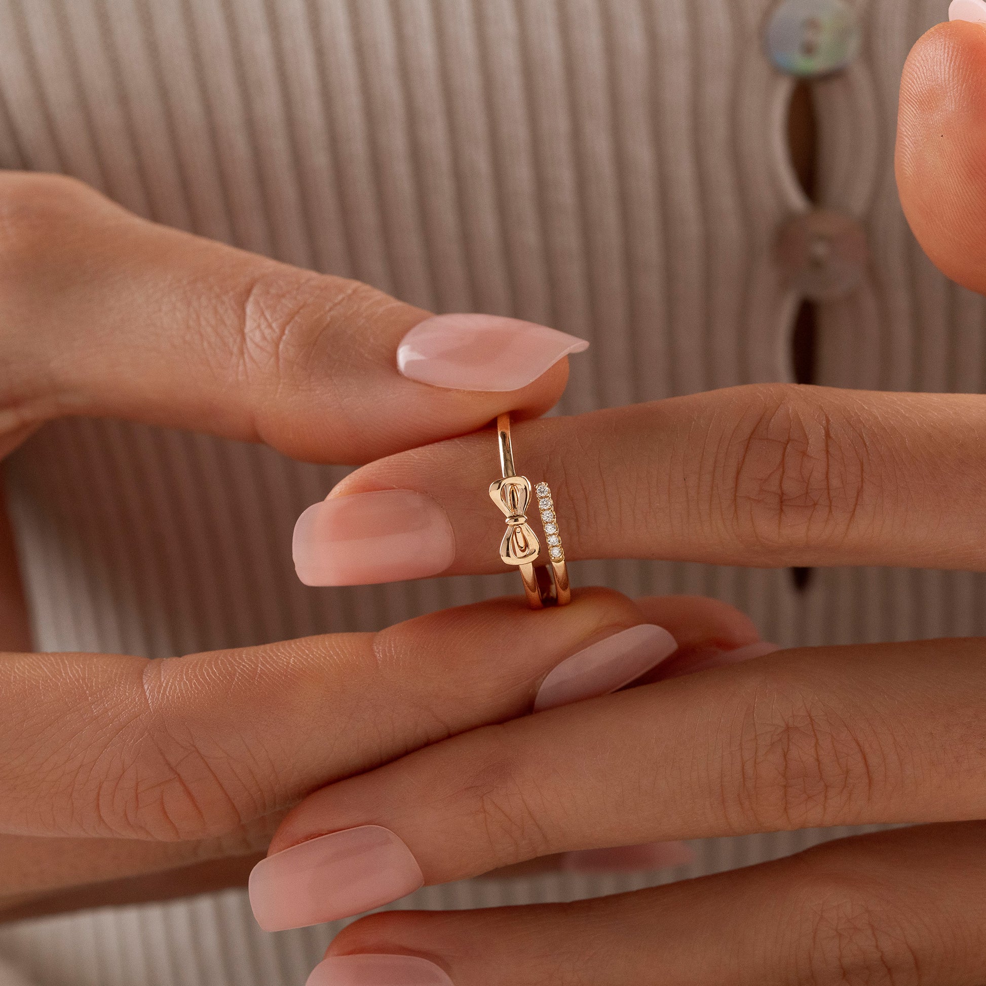 Arel Custom Jewelry 14k solid gold double band wrap ring featuring a polished bow and a pave diamond row on a model's finger.