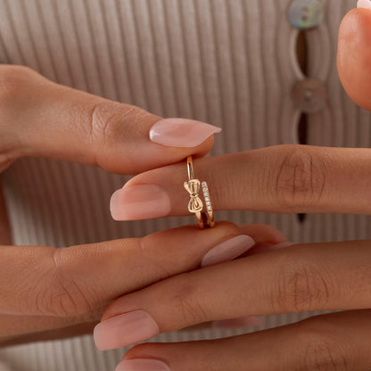 Arel Custom Jewelry 14k solid gold double band wrap ring featuring a polished bow and a pave diamond row on a model's finger.