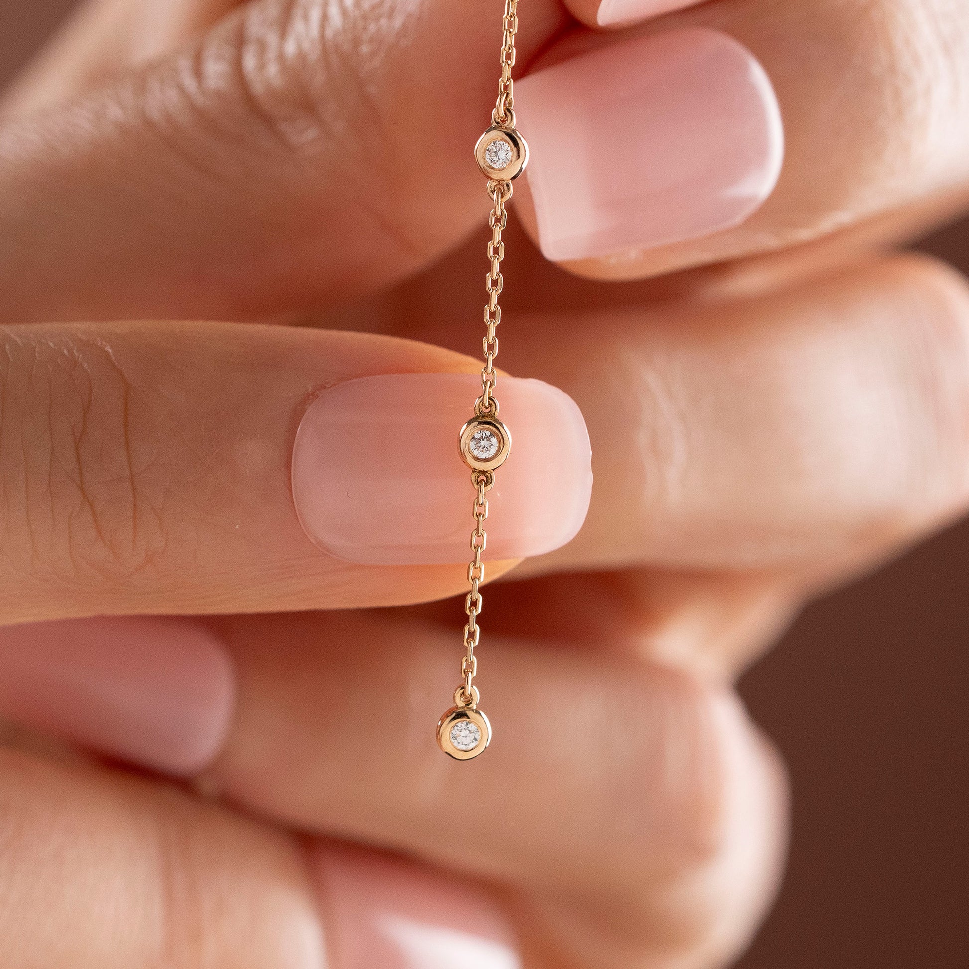 Arel Custom Jewelry 14k solid gold teardrop earring with natural diamonds on a dangling chain, worn by a model.