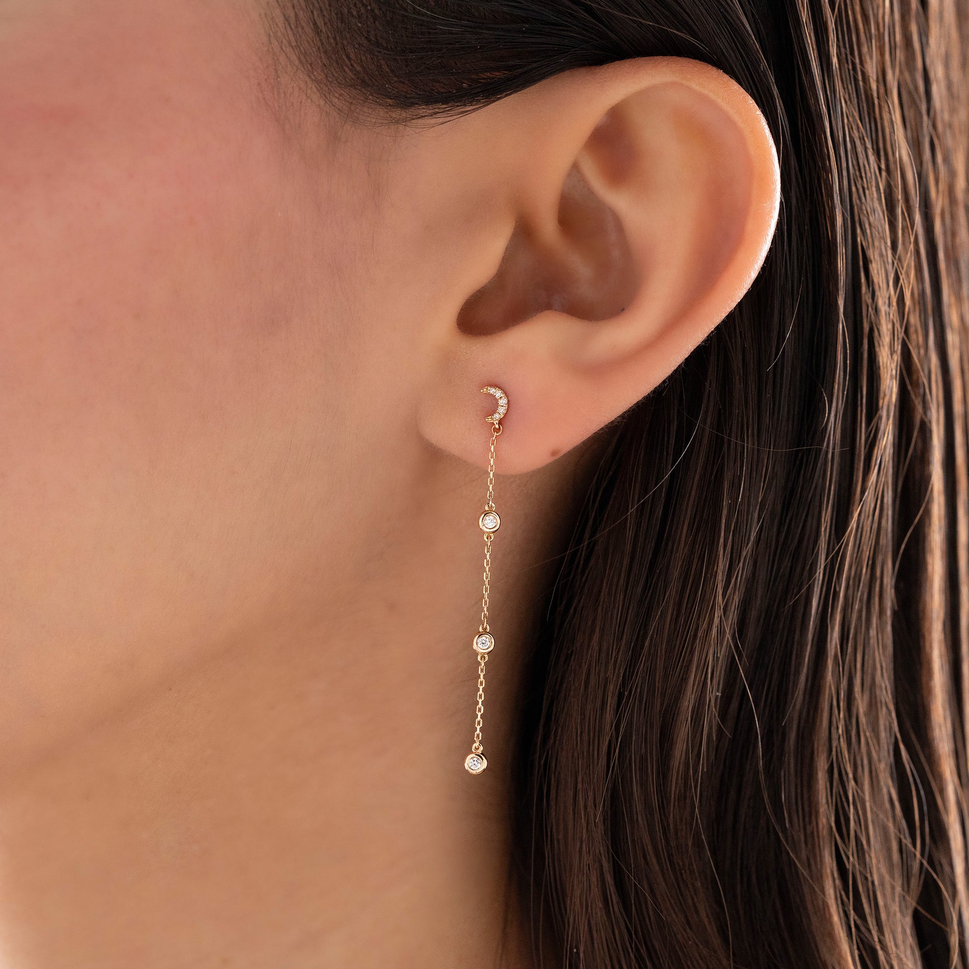 Arel Custom Jewelry 14k solid gold celestial crescent moon drop earring with dangling bezel set diamonds on a model.