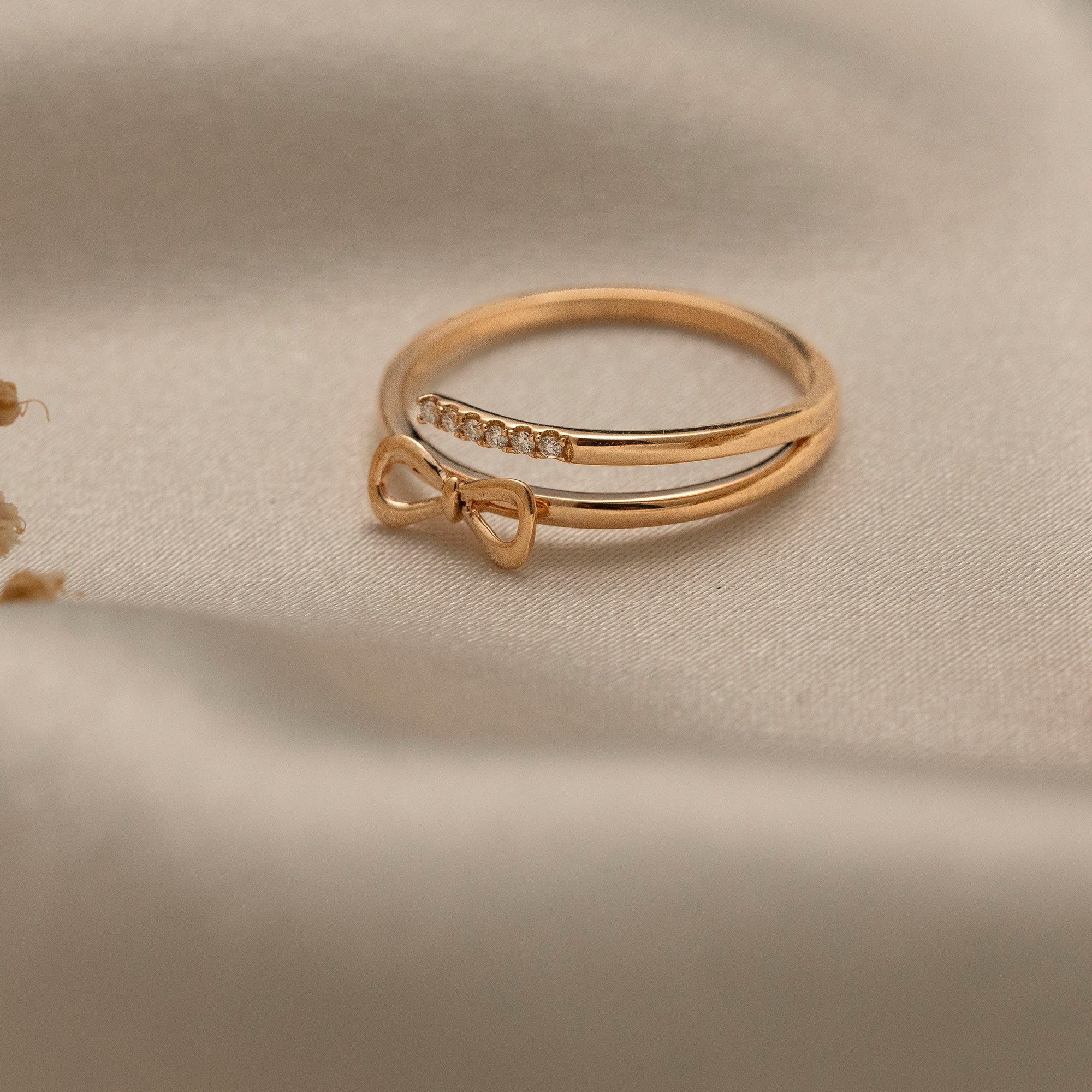 Arel Custom Jewelry 14k solid gold double band wrap ring featuring a polished bow and a pave diamond row on a model's finger.