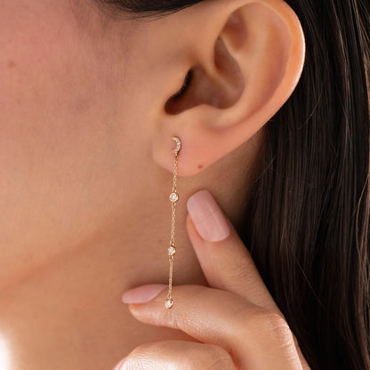 Arel Custom Jewelry 14k solid gold celestial crescent moon drop earring with dangling bezel set diamonds on a model.