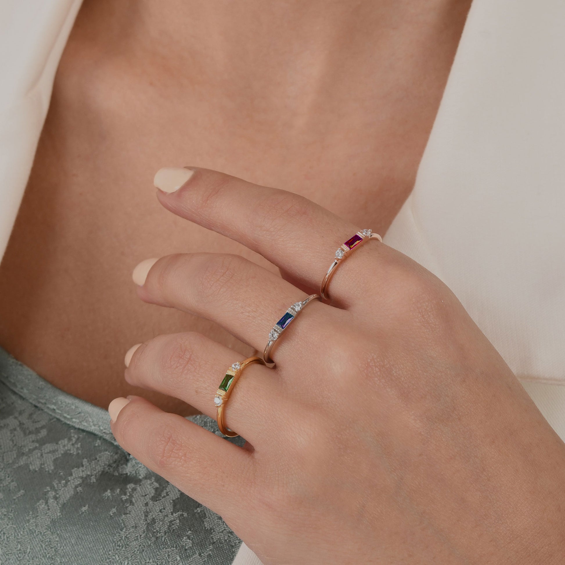 14k solid gold three stone ring featuring a 4x2mm center baguette gemstone and two 1.80mm round diamond accents on a model's hand.