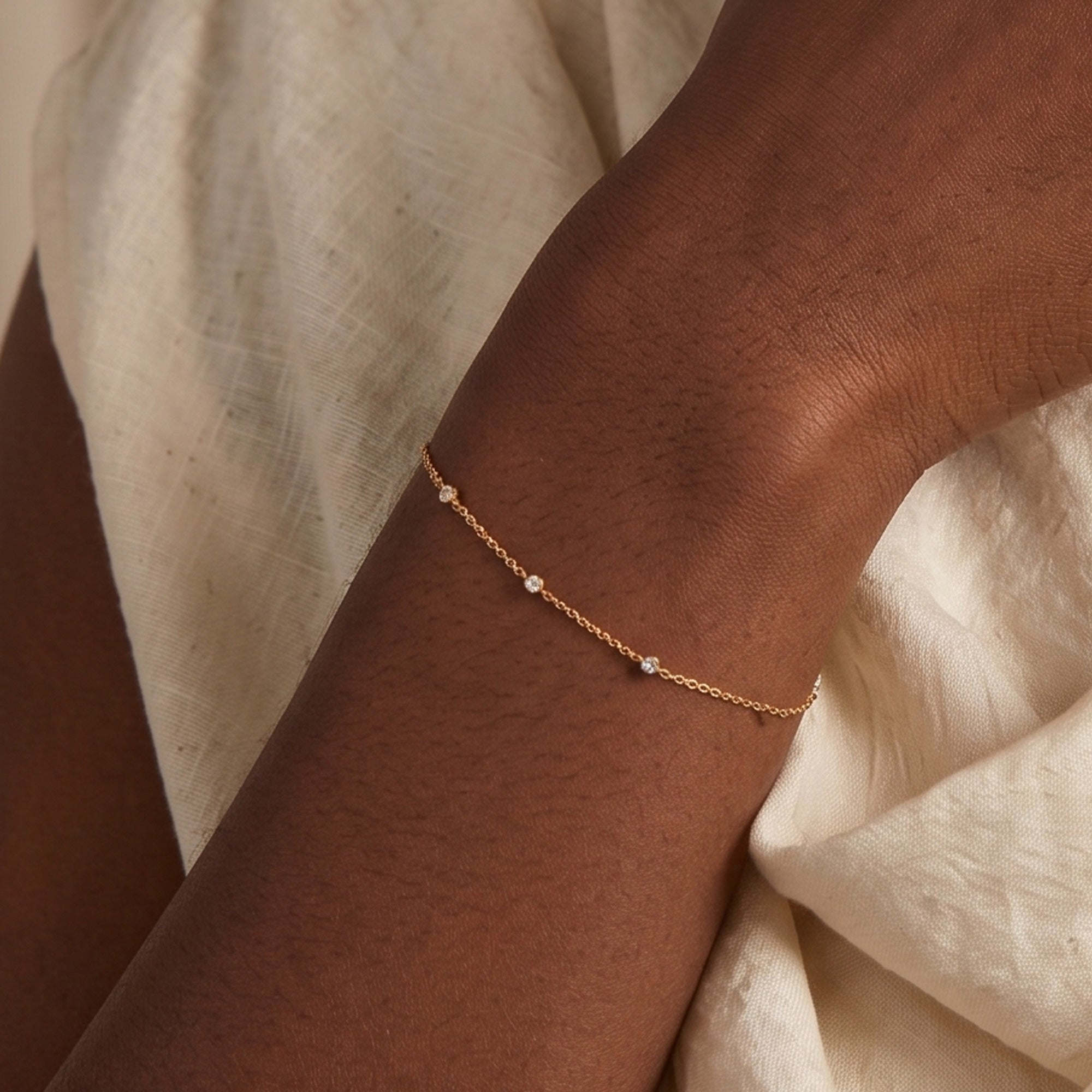 Arel Custom Jewelry 14k solid gold dainty station bracelet featuring three bezel set natural diamonds on a model's wrist
