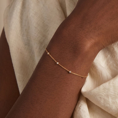 Arel Custom Jewelry 14k solid gold dainty station bracelet featuring three bezel set natural diamonds on a model's wrist