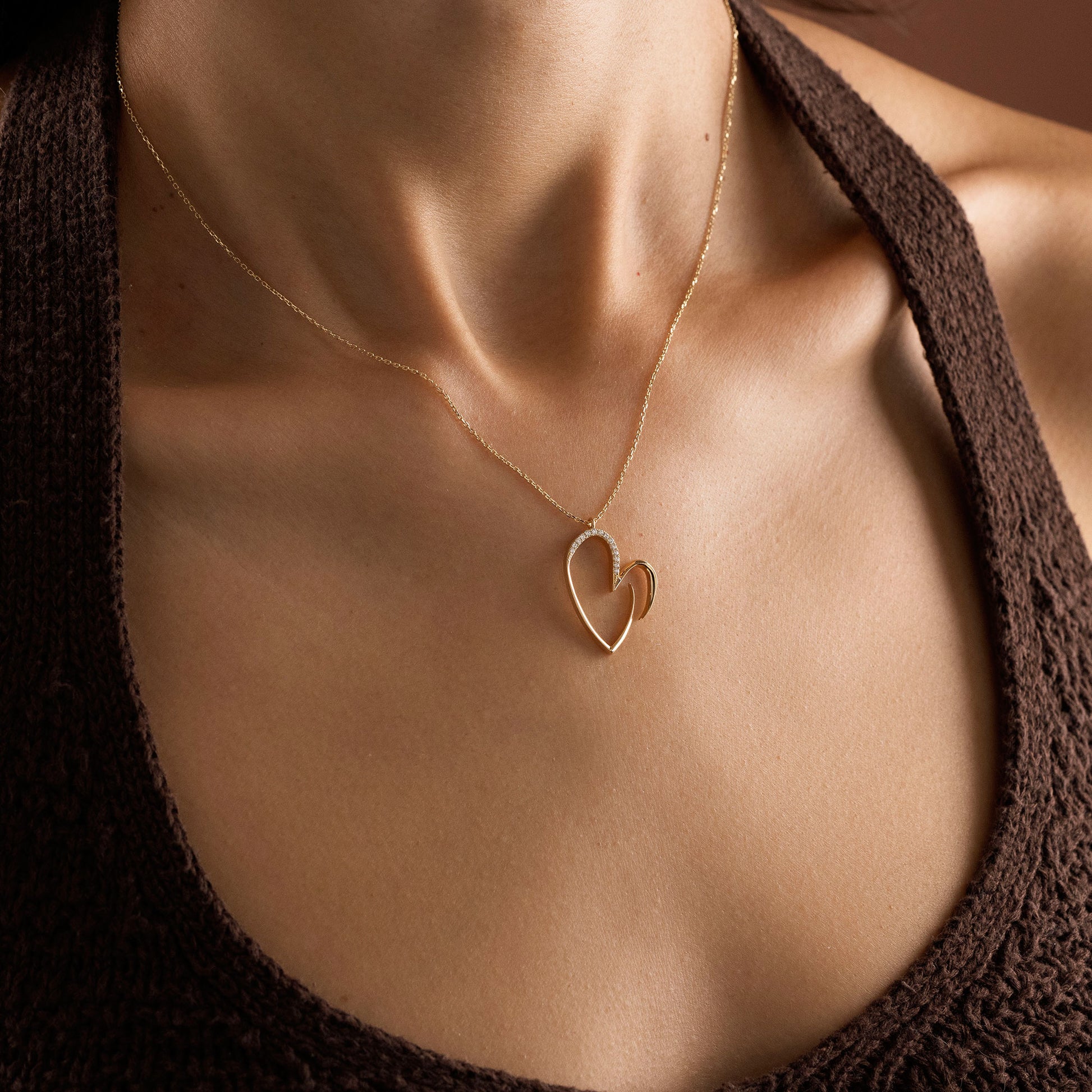 Arel Custom Jewelry 14k solid gold asymmetrical open heart necklace featuring half pave diamonds on a model.