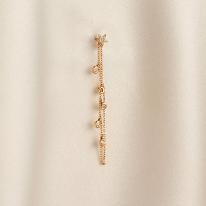 Dainty 14k gold front-to-back chain earring featuring a diamond star stud and bezel-set diamond drops on a model.