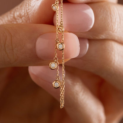 Dainty 14k gold front-to-back chain earring featuring a diamond star stud and bezel-set diamond drops on a model.