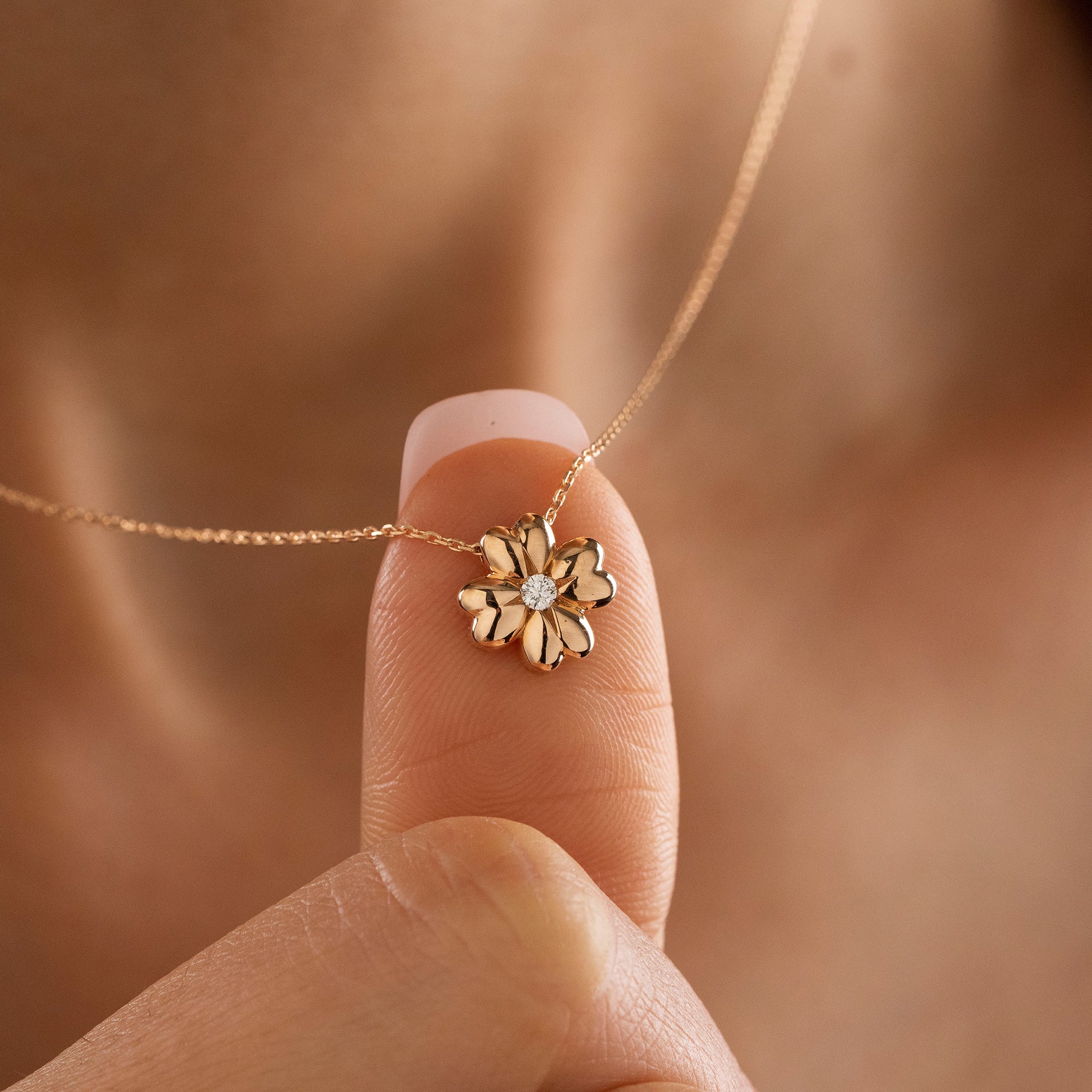 Arel Custom Jewelry 14k solid gold minimalist necklace featuring a four leaf clover pendant with a center diamond on a model.