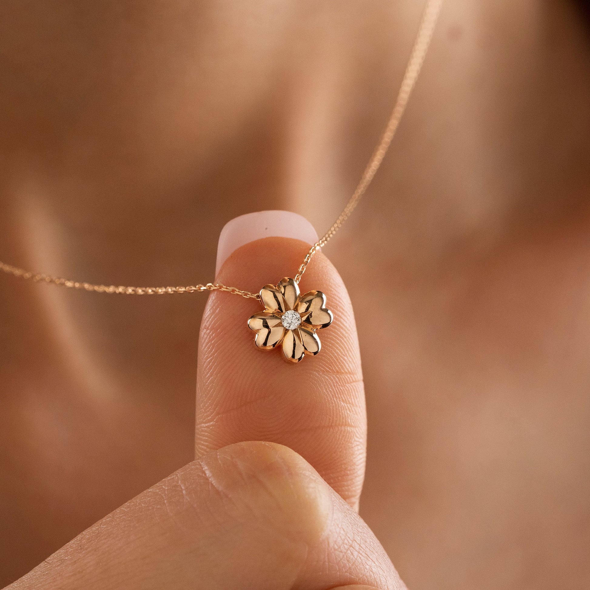 Arel Custom Jewelry 14k solid gold minimalist necklace featuring a four leaf clover pendant with a center diamond on a model.