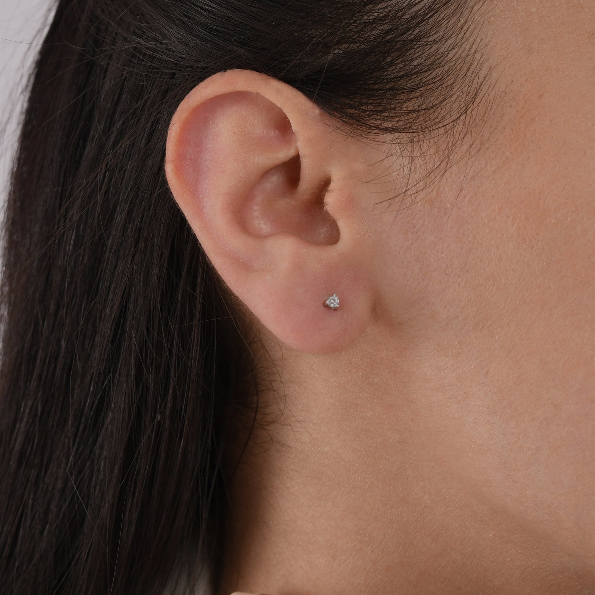 14k solid gold 3 prong diamond stud earrings featuring 2.20mm stones in rose, yellow, and white gold on a model's ear.