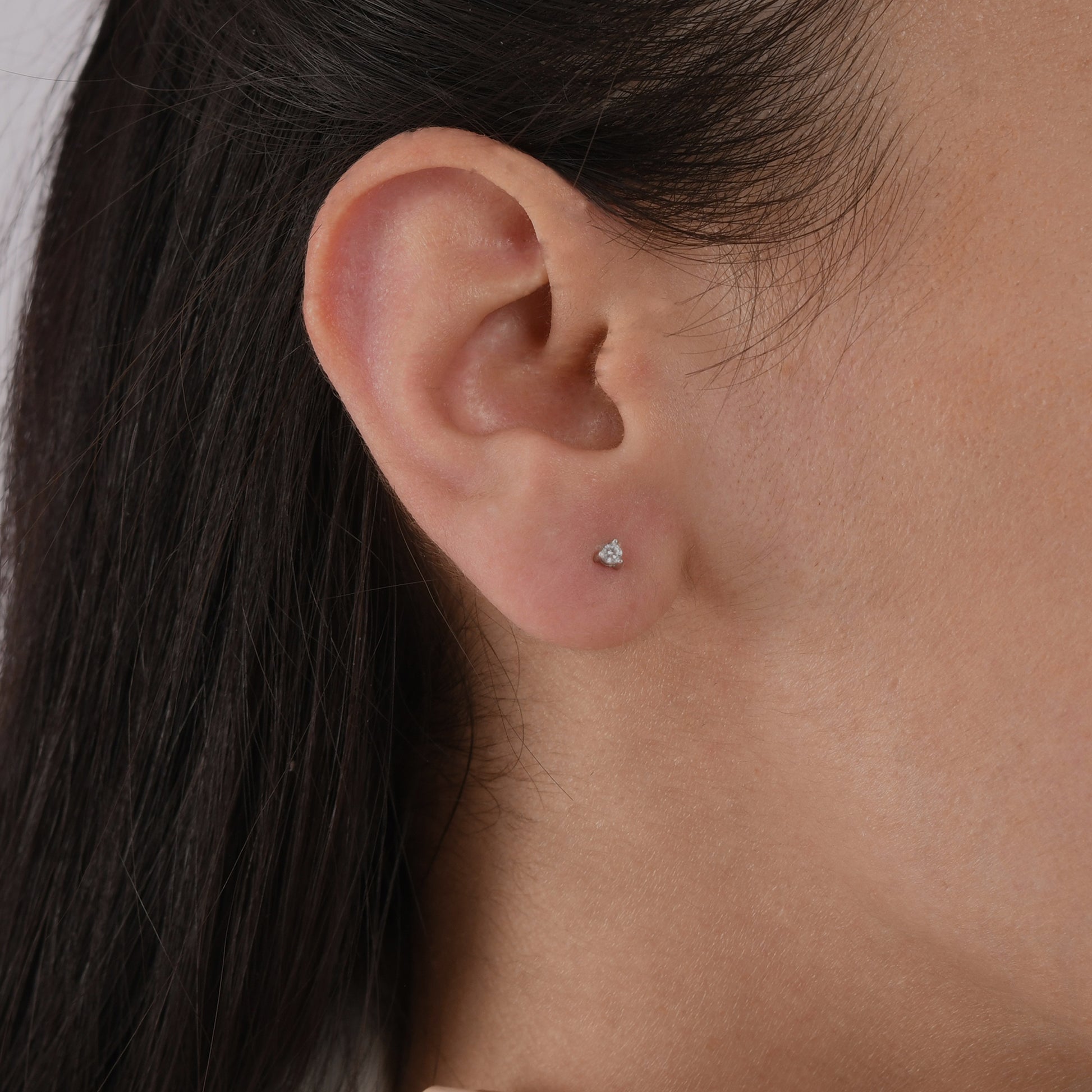 14k solid gold 3 prong diamond stud earrings featuring 2.20mm stones in rose, yellow, and white gold on a model's ear.