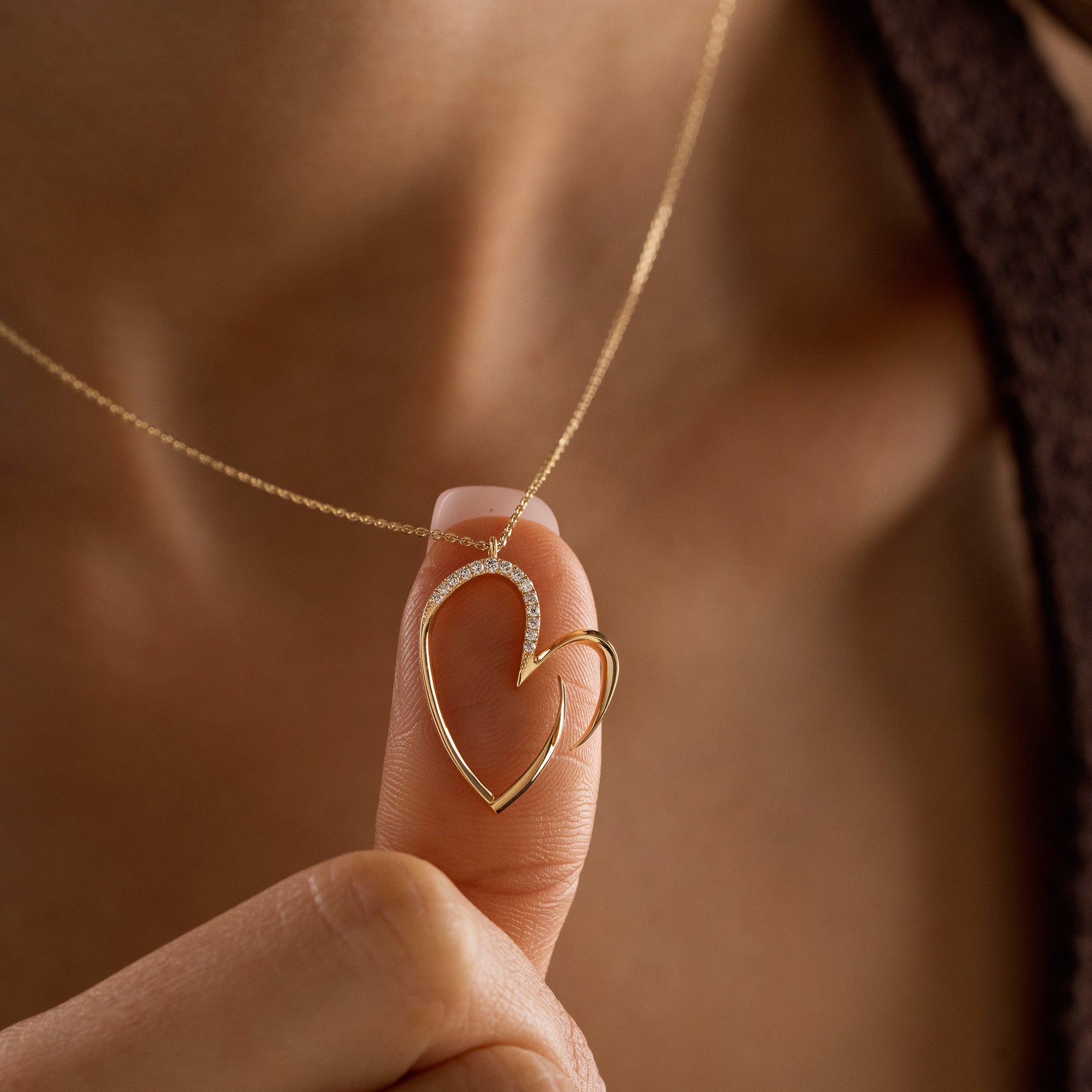 Arel Custom Jewelry 14k solid gold asymmetrical open heart necklace featuring half pave diamonds on a model.