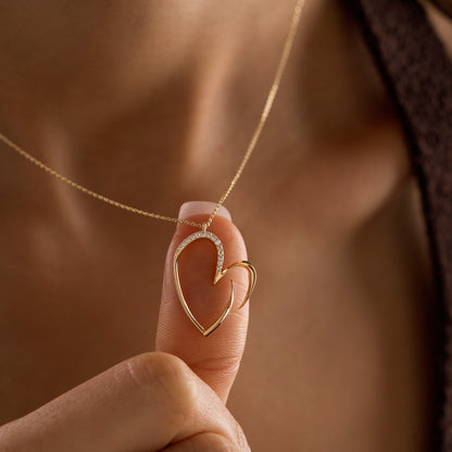 Arel Custom Jewelry 14k solid gold asymmetrical open heart necklace featuring half pave diamonds on a model.