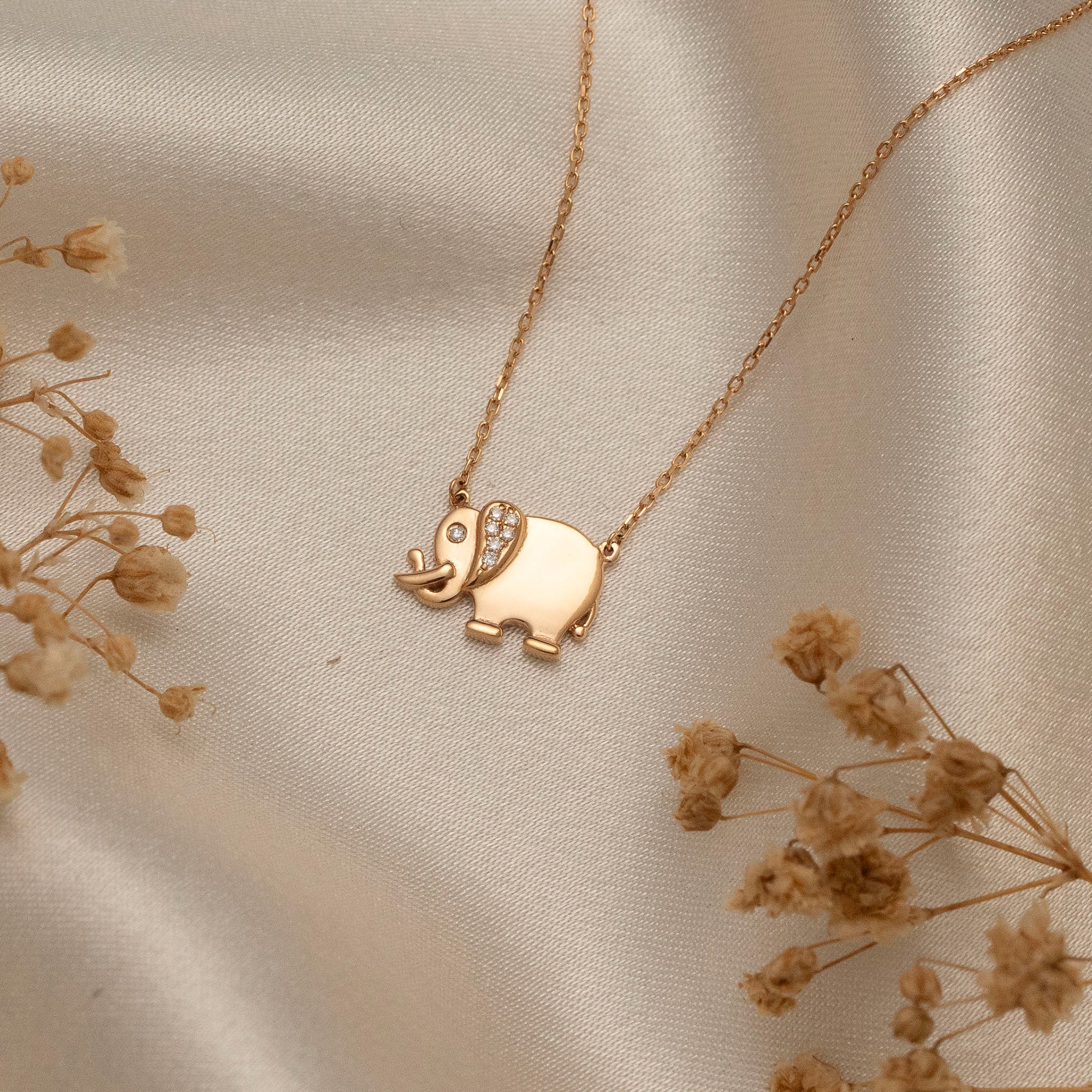 Arel Custom Jewelry 14k solid gold necklace featuring a polished elephant pendant with a pave diamond ear and trunk up on a model.