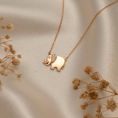 Arel Custom Jewelry 14k solid gold necklace featuring a polished elephant pendant with a pave diamond ear and trunk up on a model.