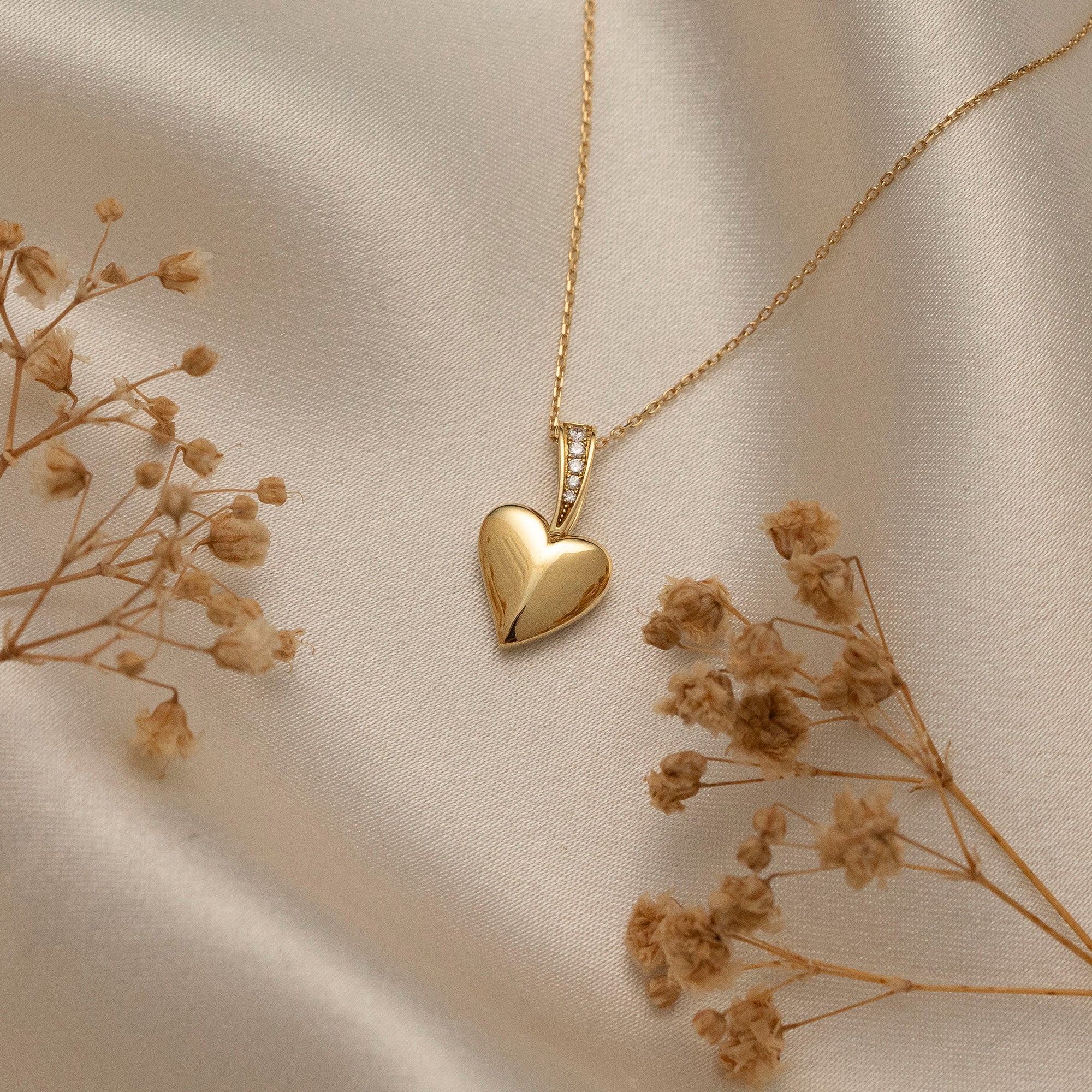 Arel Custom Jewelry 14k solid gold polished heart pendant featuring a pave diamond bail on a model.