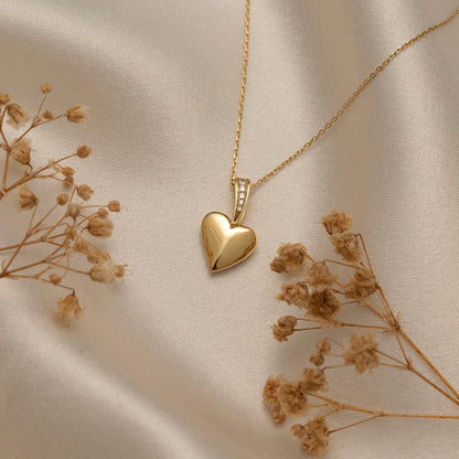 Arel Custom Jewelry 14k solid gold polished heart pendant featuring a pave diamond bail on a model.