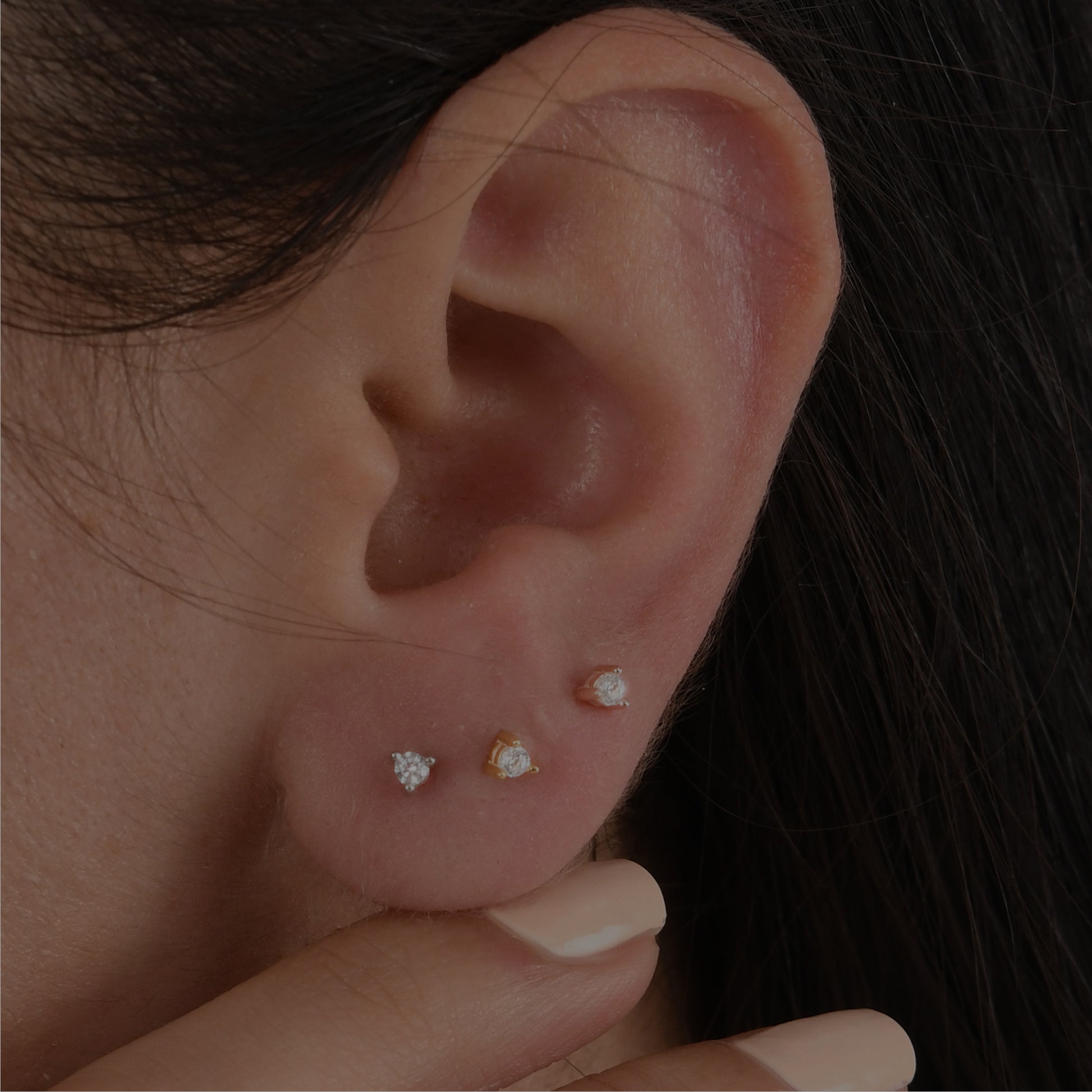 14k solid gold 3 prong diamond stud earrings featuring 2.20mm stones in rose, yellow, and white gold on a model's ear.