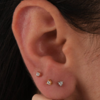 14k solid gold 3 prong diamond stud earrings featuring 2.20mm stones in rose, yellow, and white gold on a model's ear.