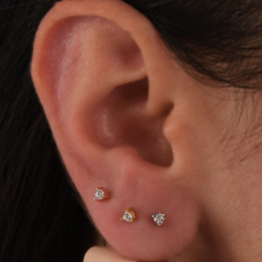 14k solid gold 3 prong diamond stud earrings featuring 2.20mm stones in rose, yellow, and white gold on a model's ear.