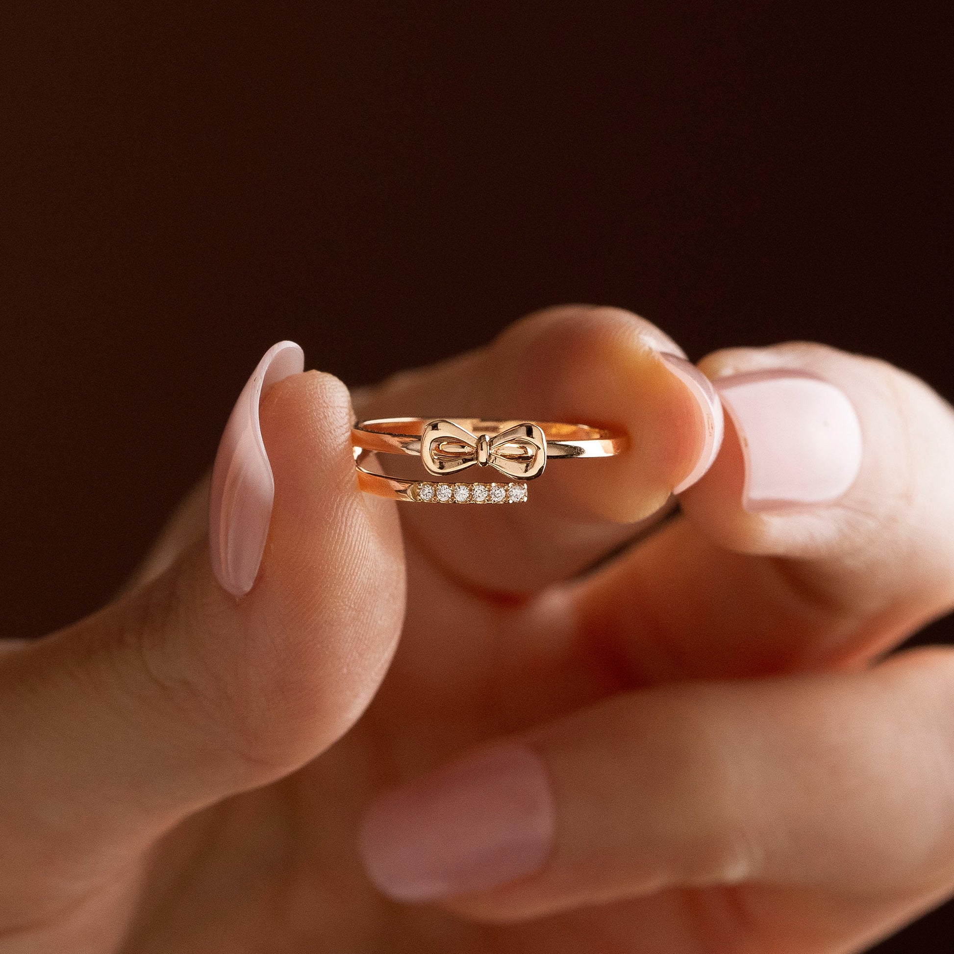 Arel Custom Jewelry 14k solid gold double band wrap ring featuring a polished bow and a pave diamond row on a model's finger.