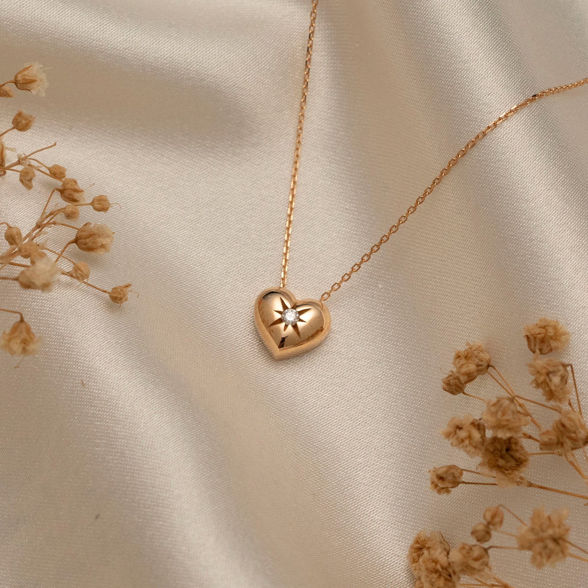 Arel Custom Jewelry 14k solid gold necklace featuring a polished puffed heart pendant with a starburst set center diamond on a model.