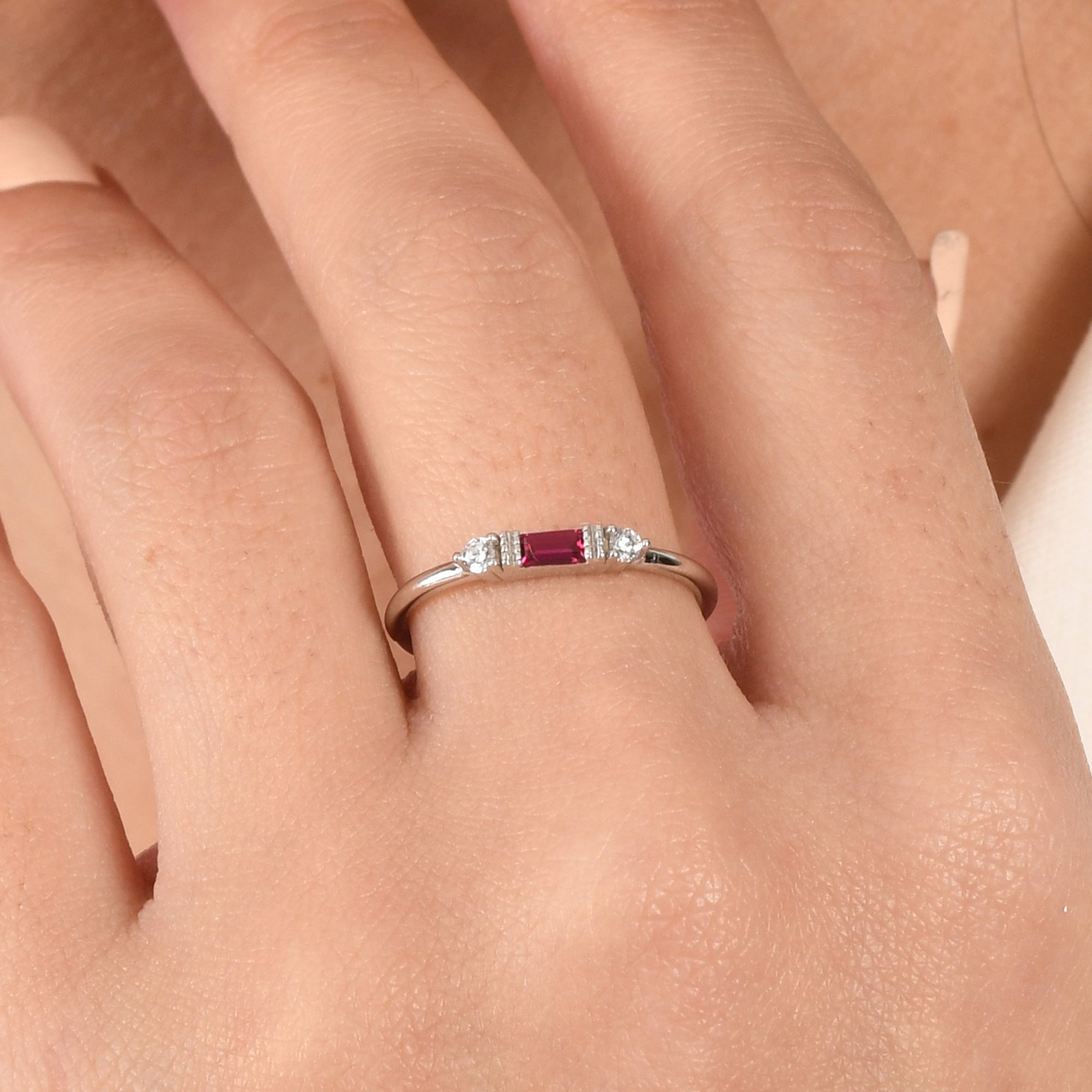 14k solid gold three stone ring featuring a 4x2mm center baguette gemstone and two 1.80mm round diamond accents on a model's hand.