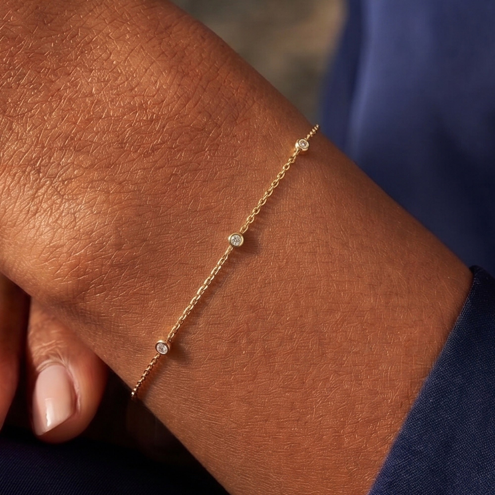 Arel Custom Jewelry 14k solid gold dainty station bracelet featuring three bezel set natural diamonds on a model's wrist