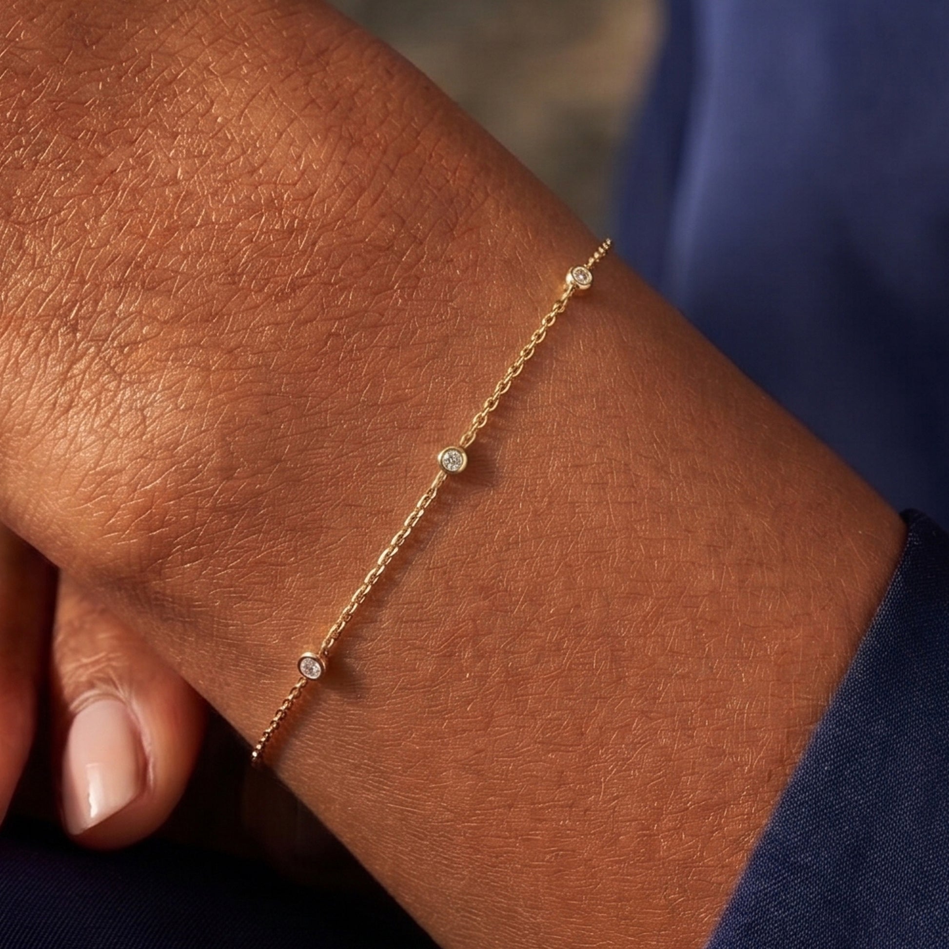 Arel Custom Jewelry 14k solid gold dainty station bracelet featuring three bezel set natural diamonds on a model's wrist