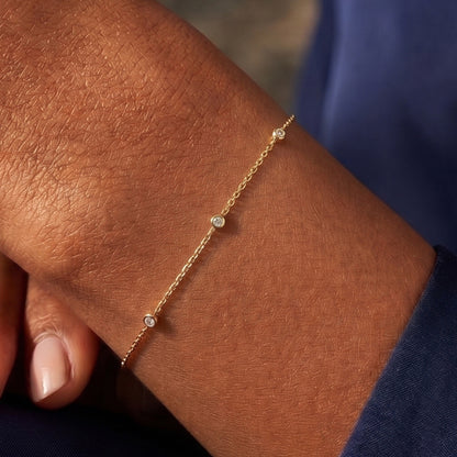 Arel Custom Jewelry 14k solid gold dainty station bracelet featuring three bezel set natural diamonds on a model's wrist
