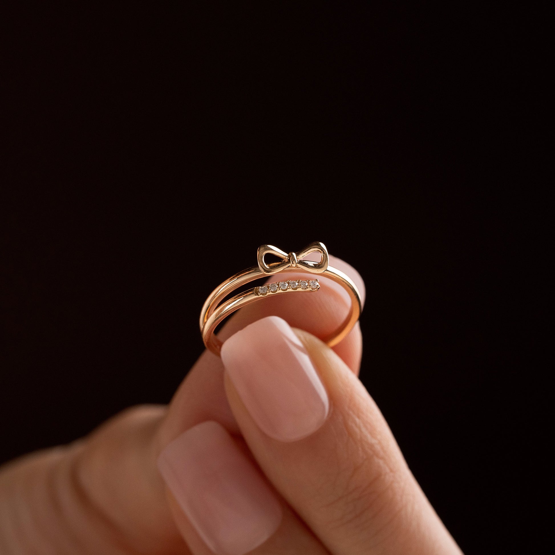 Arel Custom Jewelry 14k solid gold double band wrap ring featuring a polished bow and a pave diamond row on a model's finger.