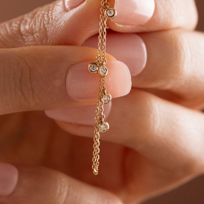 Arel Custom Jewelry 14k solid gold drape chain earring featuring a pave diamond evil eye stud and bezel diamonds on a model.
