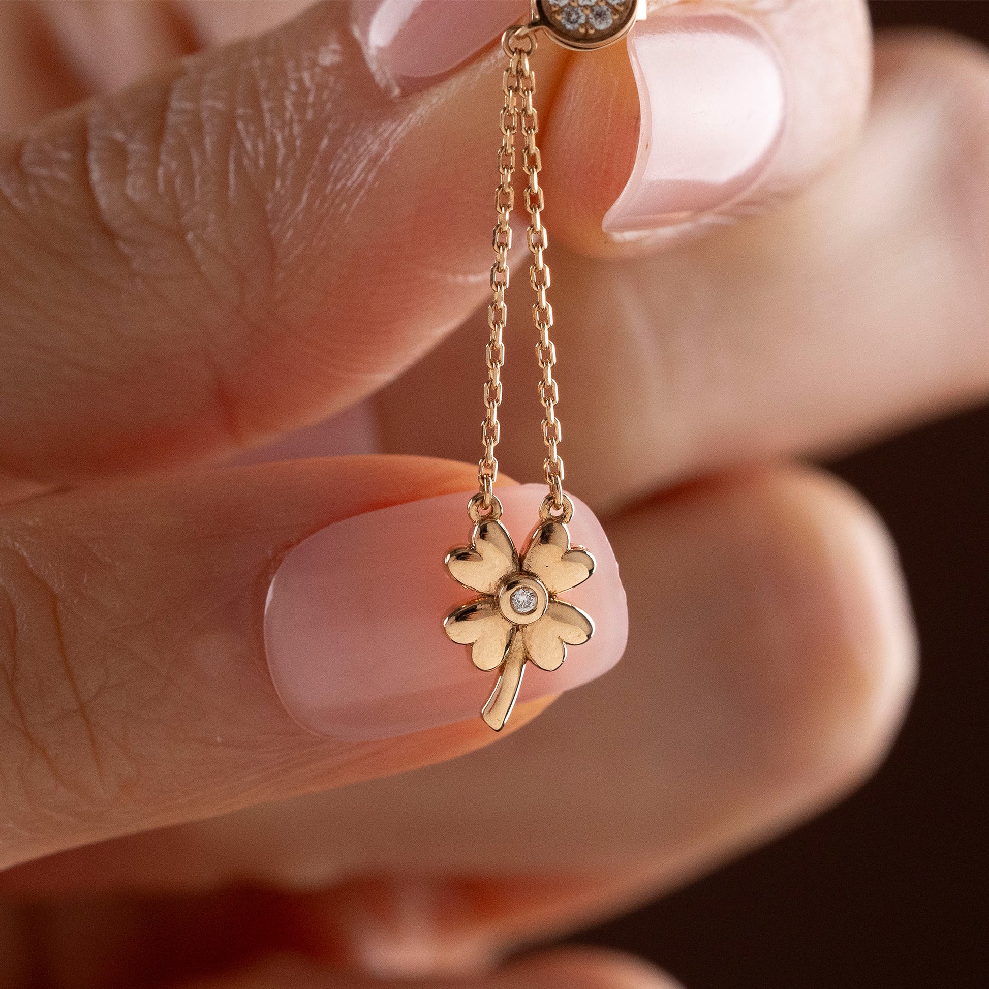 Arel Custom Jewelry 14k solid gold dangle earring with a pave diamond stud and double chain clover drop on a model.